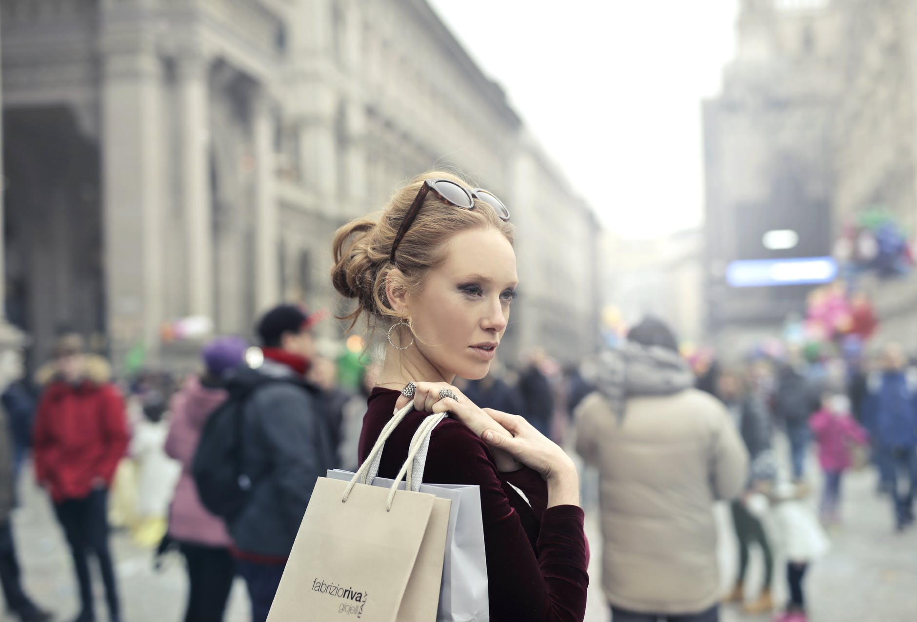 woman wearing maroon long sleeved top carrying brown and white paper bags in selective focus photography